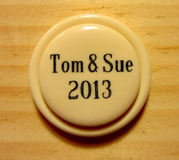 Cream-colored Custom Two Line Brag Button With ’tom & Sue 2013’ In Black Text